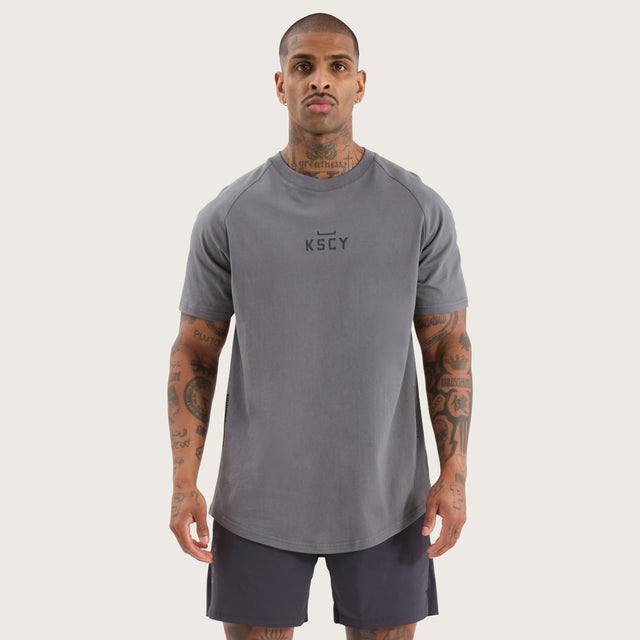 Model wears Vital Raglan Dual Curved Tee Charcoal T-Shirts in Grey - Image 1