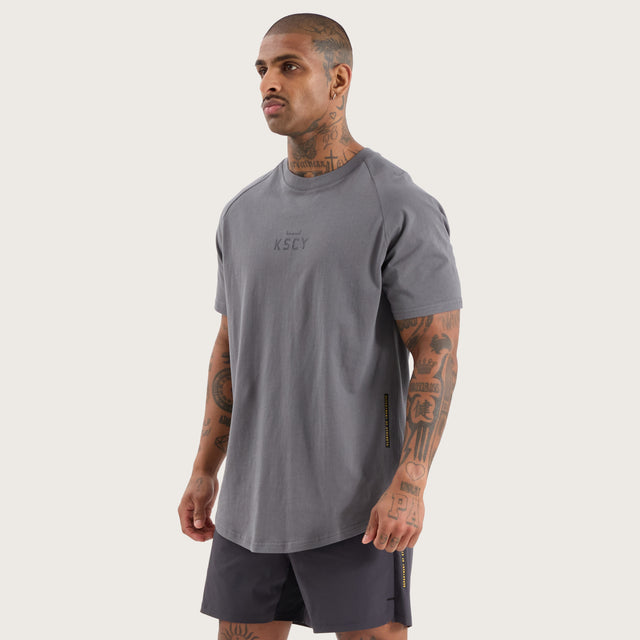 Model wears Vital Raglan Dual Curved Tee Charcoal T-Shirts in Grey - Image 4