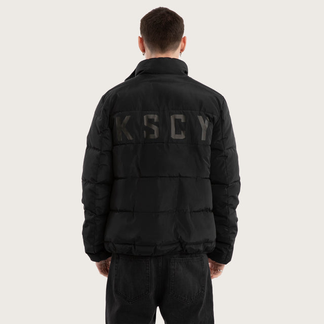 Model wears Solitary Puffer Jacket Jet Black Jackets in Black - Image 3