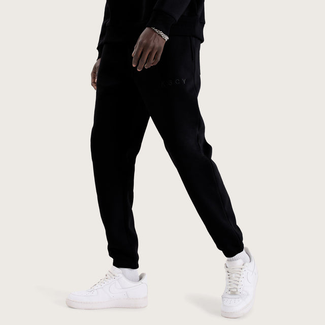 Model wears Kelsey Trackpant Jet Black Trackpants in Black - Image 1