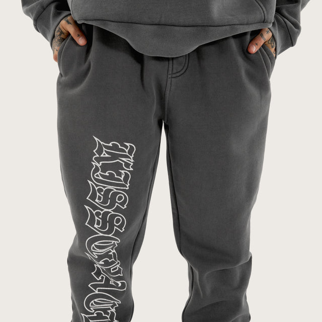 Model wears Genesis Trackpant Pigment Charcoal Trackpants in Grey - Image 6