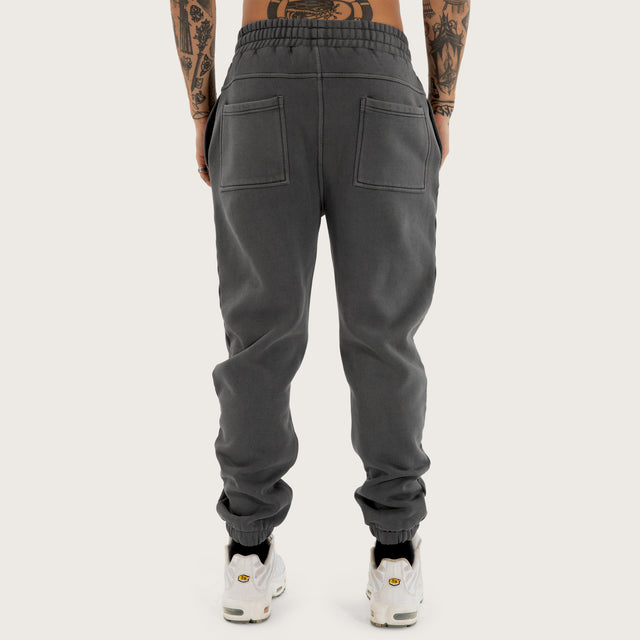 Model wears Genesis Trackpant Pigment Charcoal Trackpants in Grey - Image 7