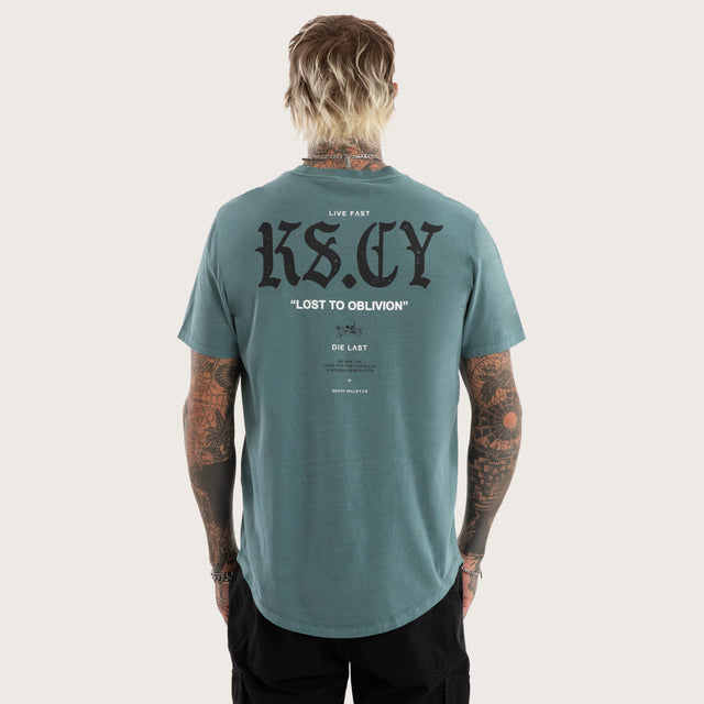Model wears England Curved Hem Tee in Green T-Shirts in Green - Image 1
