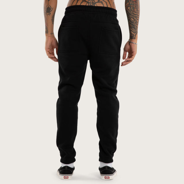 Model wears Sinner Trackpant Jet Black Trackpants in Black - Image 5