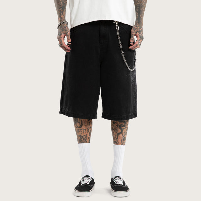 Model wears Luke Walker Tense K7 Super Baggy Jorts Black Shorts in Black - Image 6