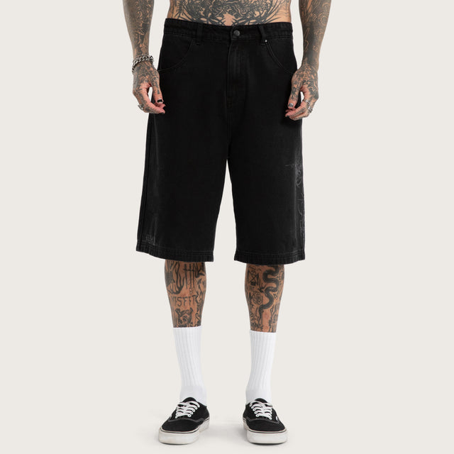Model wears Luke Walker Tense K7 Super Baggy Jorts Black Shorts in Black - Image 2