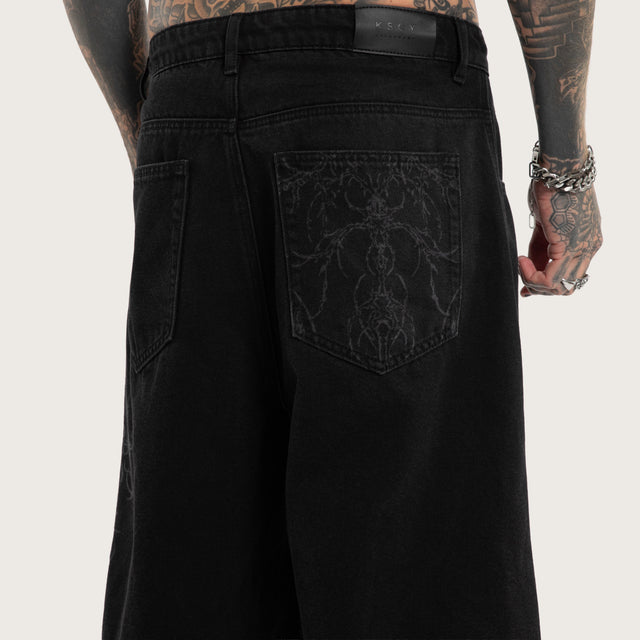 Model wears Luke Walker Tense K7 Super Baggy Jorts Black Shorts in Black - Image 4